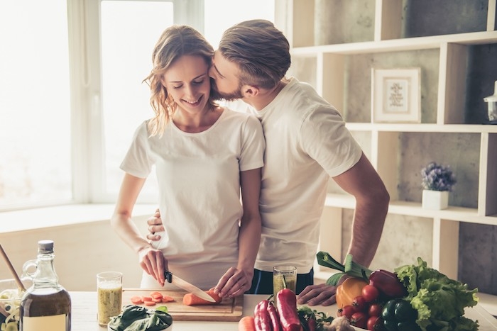 une couple qui fait la cuisine ensemble des legumes sur la table que faire pour saint valentin