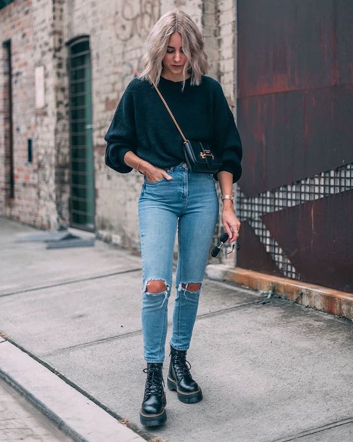 une femme avec jean déchire pull noir et des bottines style doc martens