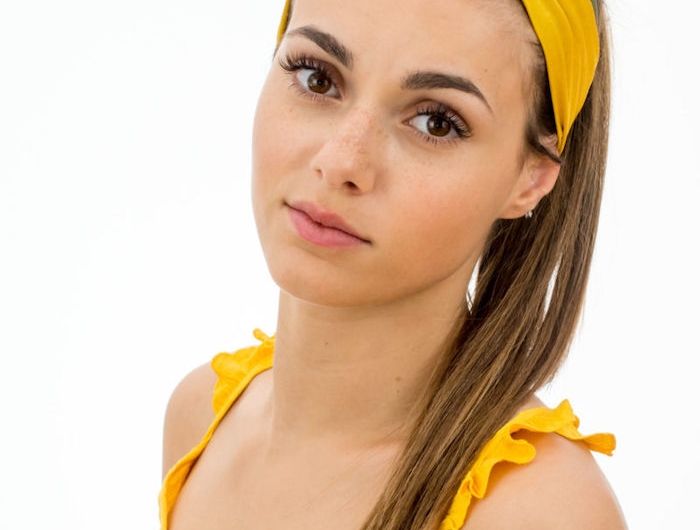 une femme en top jaune avec bandeau pour cheveux en jaune et verte