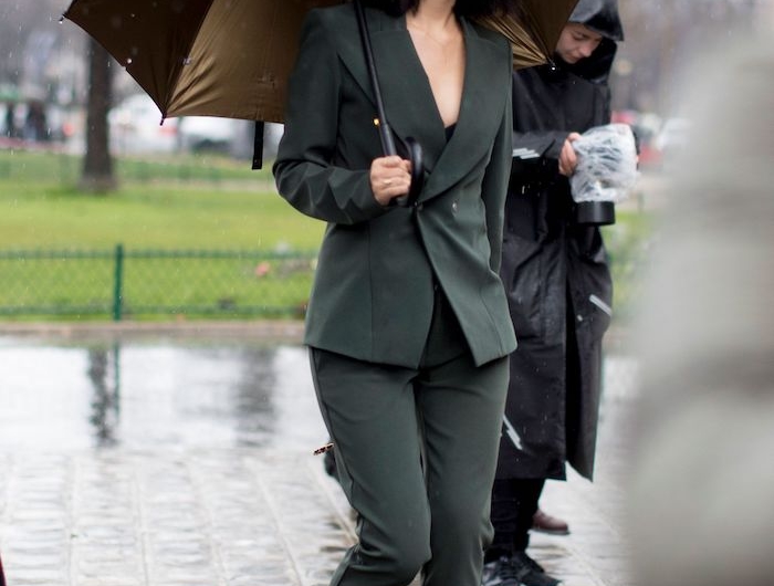 une femme qui porte un tailleur avec longeur au dessus des chevilles et porte un parapluie