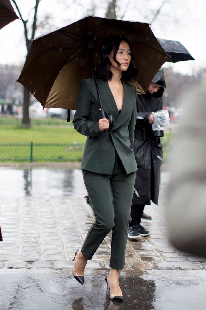 une femme qui porte un tailleur avec longeur au dessus des chevilles et porte un parapluie