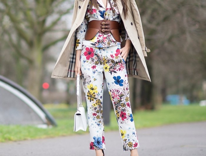 une femme vetue en ensemble tailleur chic aux motifs floraux avec une ceinture large en cuir et manteau burrbery