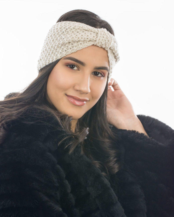une femme vetue en manteau a fourrure avec un bandeau d hiver tricoté en noeud