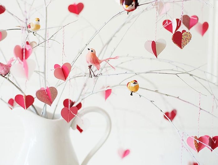 une vase blanche avec des branches et des oiseaux décoratifs penchée sur eux surprise saint valentin