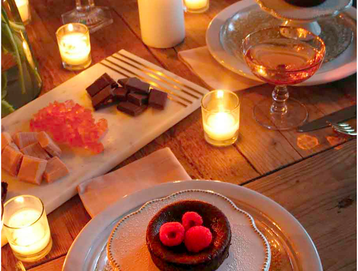 bougie saint valentin sur une table romantique avec des desserts dans des assiettes et des fleurs dans une vase.jpg