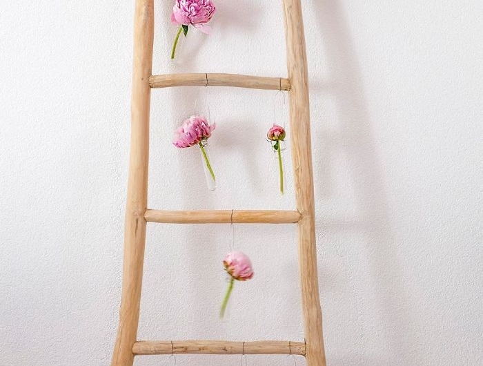branches de bois assemblés en échele décorative décorée de fleurs suspendues deco chambre tendance de printemps