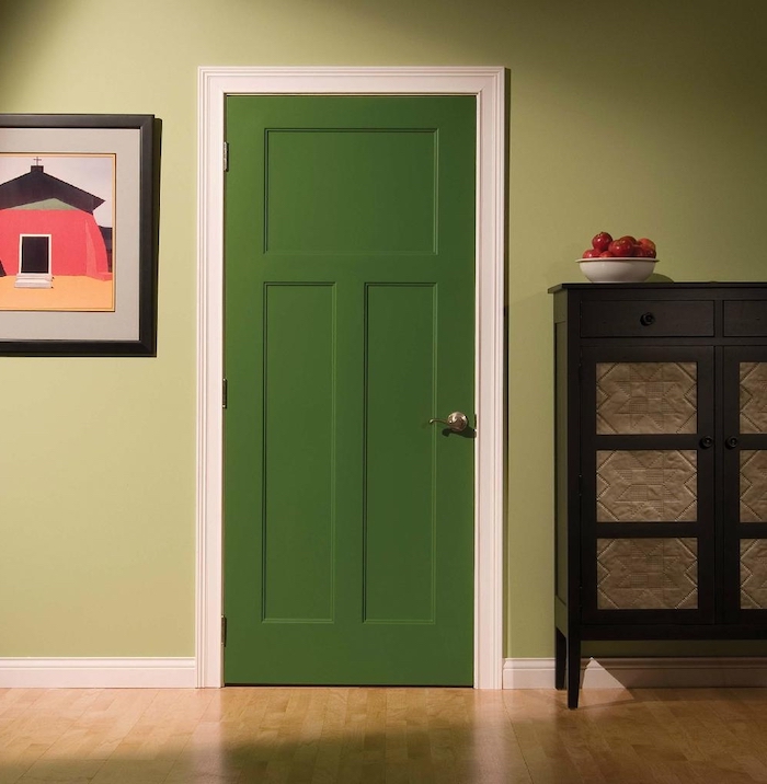 décoration couloiur d entré avec une porte verte dans un cadre blanc entre un tableu et un commode en bois