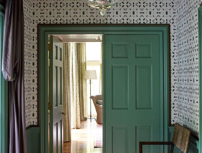 décoration couloiur d entrée avec des papier peint a motifs une porte en vert pastel et un banc en bois