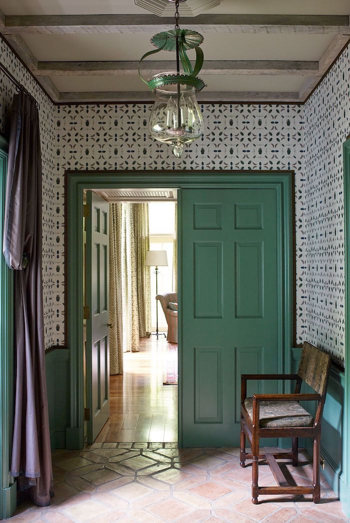 décoration couloiur d entrée avec des papier peint a motifs une porte en vert pastel et un banc en bois