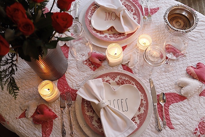diner aux chandelles sur une nappe blanche décorée de petits coeurs en tissu en une vase aux roses rouges