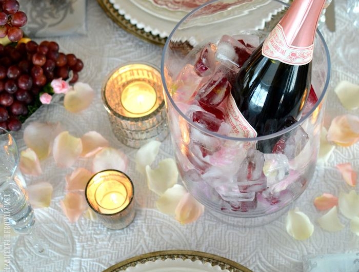 diner romantique avec deux assiettes en porcelaine un seau de champagne des bougies et petales de rose