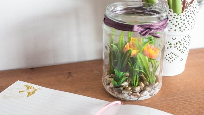 faux terrarium dans pot en verre avec du gravier au fond et des fleurs artificielles deco paques printaniere fleurie