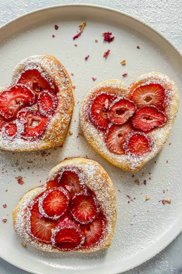 gâteau à la fraise en forme de coeur tartalette pâte feuilletée fraises et sucre glace dans assiette