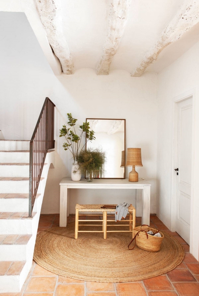 hall d entrée tapis rond jute miroir escalier blanc et bois lampe fibre végétale vase blanc