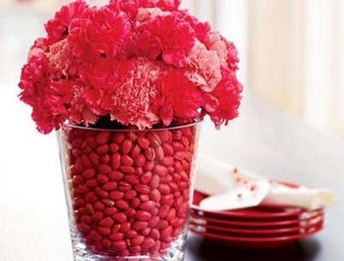 idée de décoration pour saint valentin avec un vase remplie de dragées rouges avec des fleurs piqués