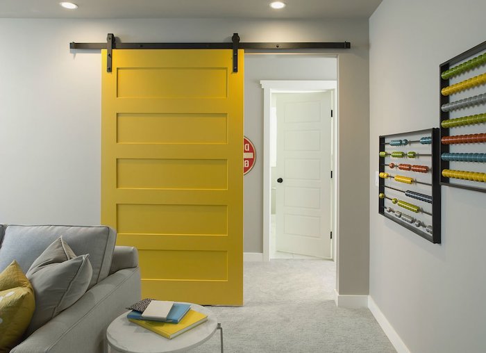 peindre une porte intérieure glissante en couleur jaune lumineux dans la salle de sejour aveec des coussins jaune et cananpé gris
