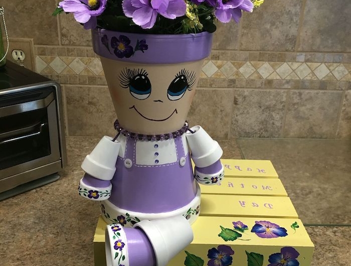 personnage en pot de fleur posé sur le comptir dans la cuisine et peint en couleurs violets