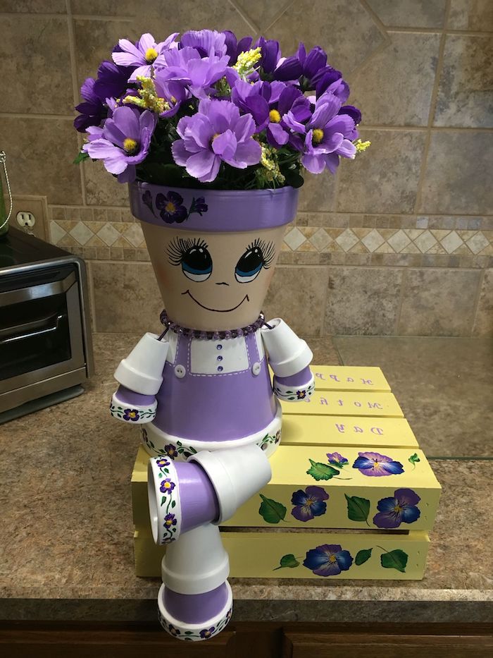 personnage en pot de fleur posé sur le comptir dans la cuisine et peint en couleurs violets