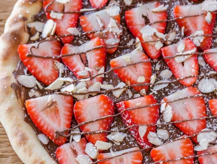 pizza maison sucrée à base de nutella et fraise avec des amandes hachés faire un dessert original au chocolat
