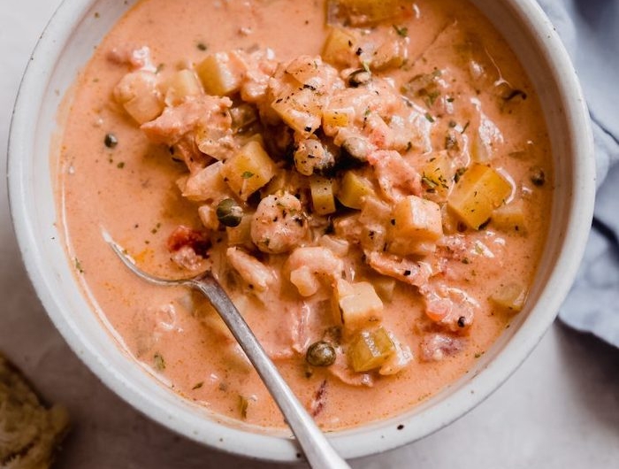 recette a base de saumon une soupe avec de mais servie dans un bol et des tranches de pain
