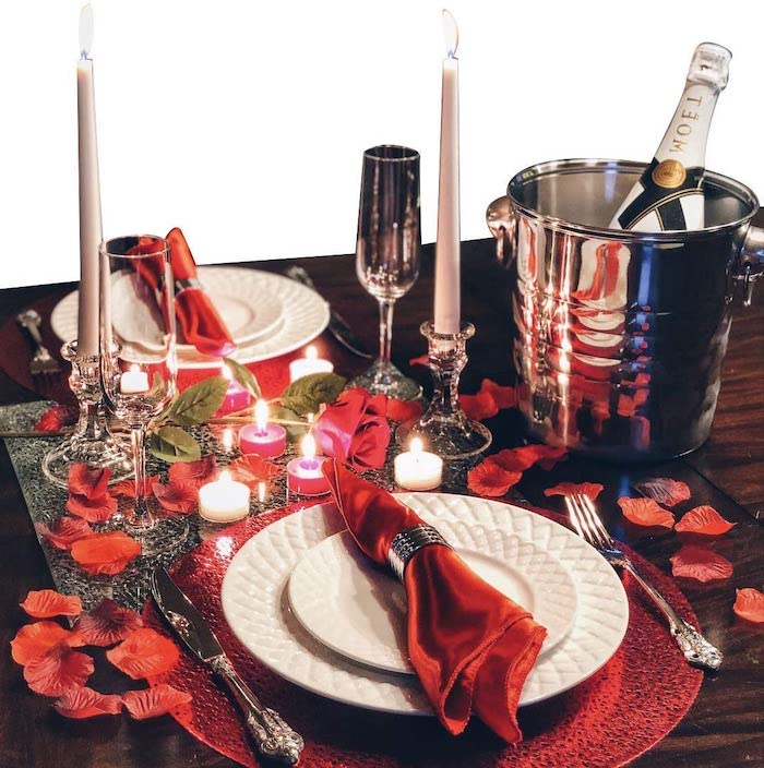 repas romantique une idée de mettre la table avec des pétales de rose et des bousies des serviettes rouges dans deux assiettes