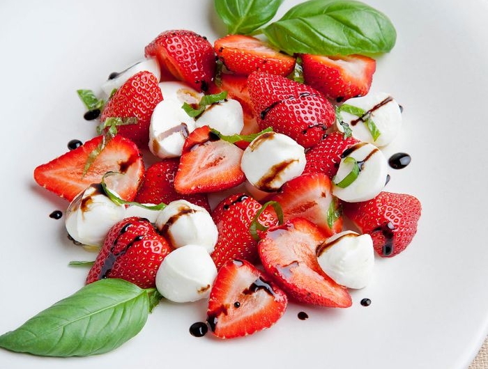 salade de fraises aux boules de mozzarella basilic et du basilic frais haché dans assiette blanche