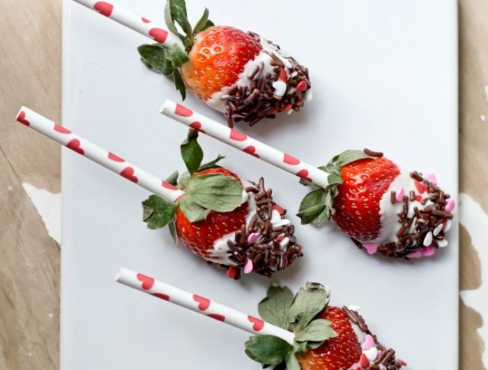 sucette à la fraise au chocolat blanc couvert de vermicelles chocolat et des coeurs de sucre dans assiette
