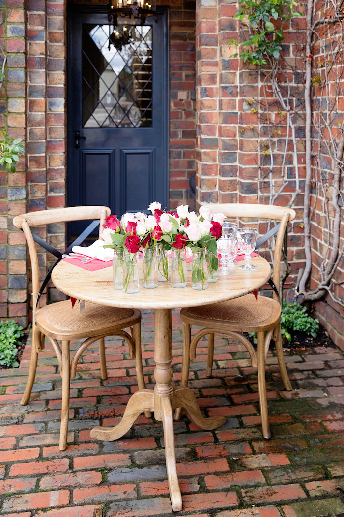 table romantique en dehors pour la fete de saint valentin décoré des nombreuses vases aux roses
