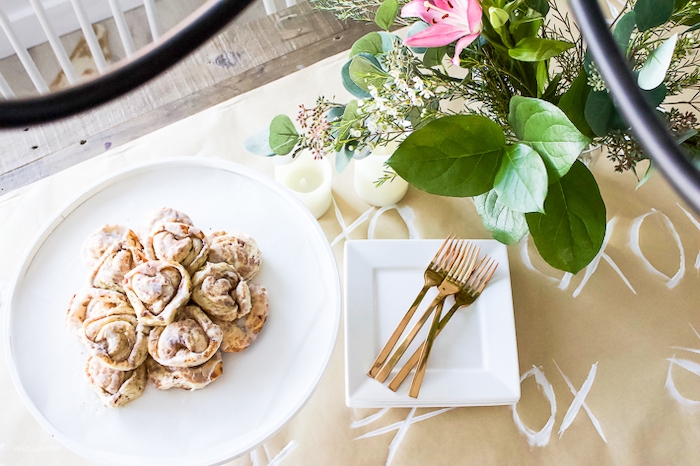 table romantique pour saint valentin avec une nappe en papier et des rouleaux a la canelle dans une assiette