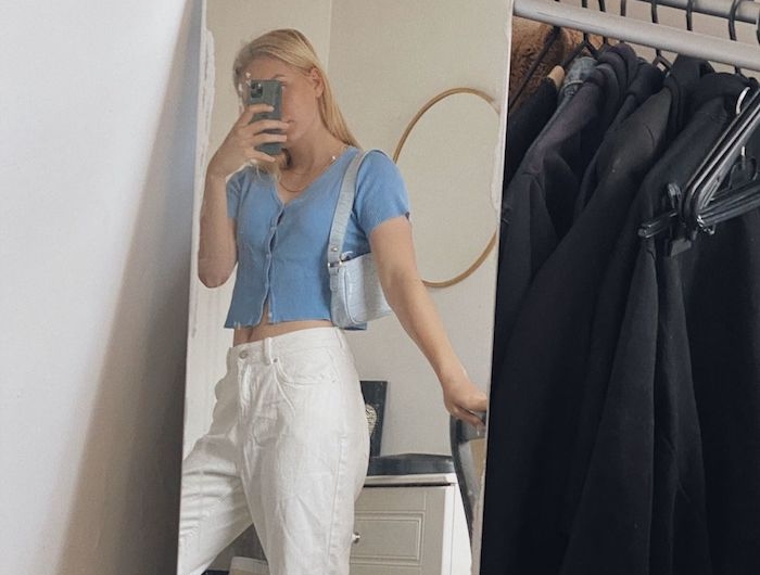 tenue avec jean mom blanc une femme qui se prend une photo dans le miroir vetue en top bleu