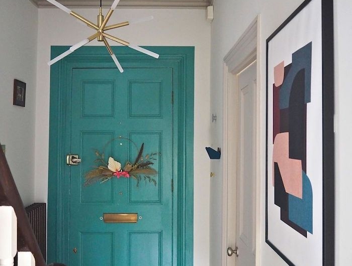 un couloiur avec des murs blanc et une porte turquoise tableu devant l escalier