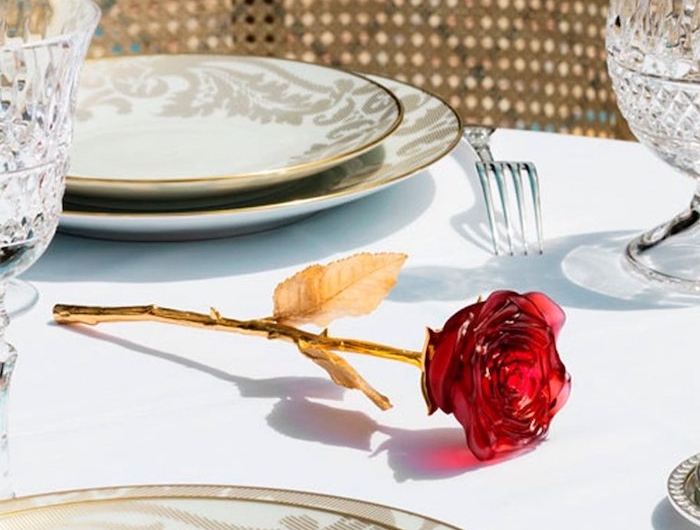 une rose cristal sur une table mis pour diner avec des assiettes en porcelaine