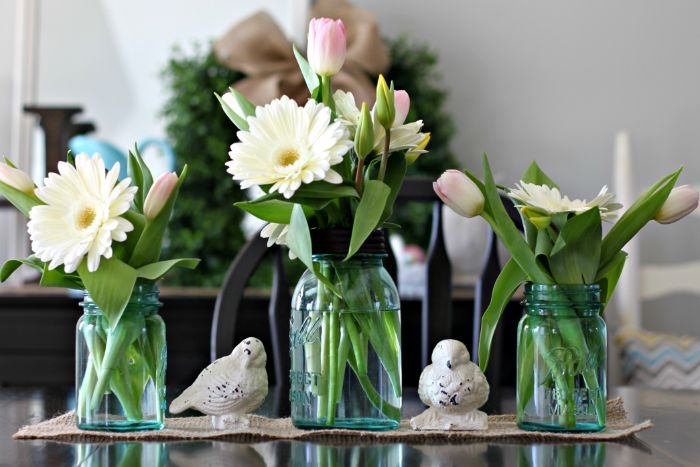 vase en bocal et pot de fleur sur un chemin de table en jute et des figurines d oiseaux originales