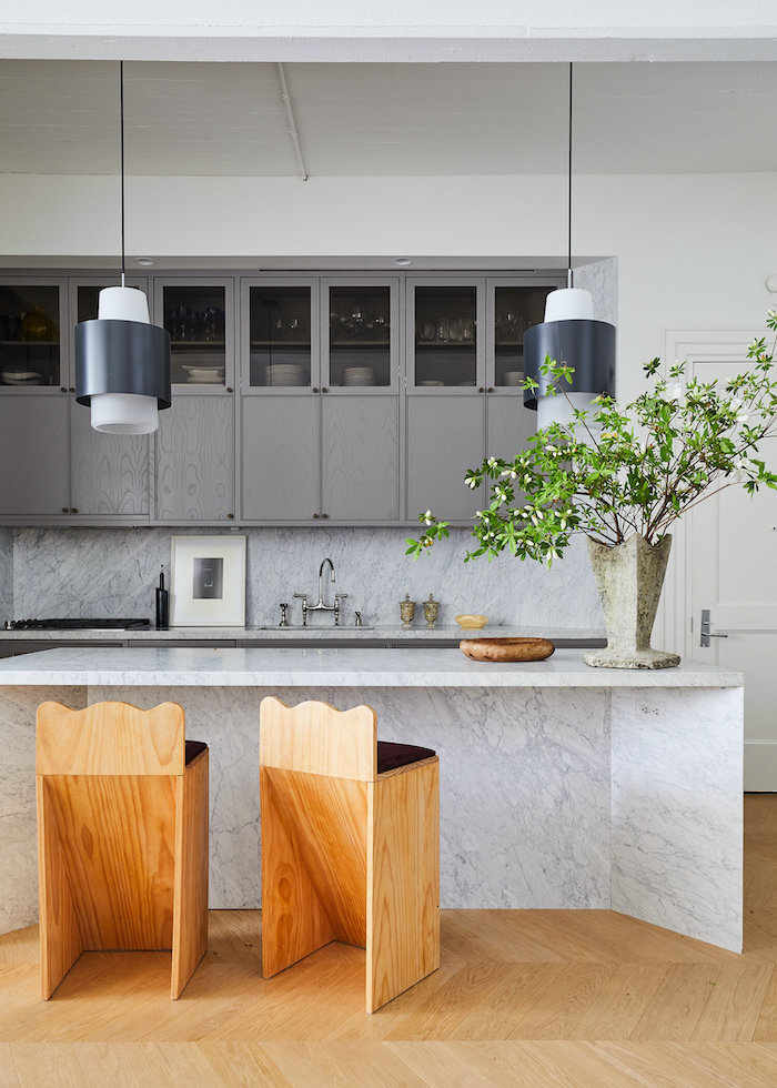 aménager petite cuisine fermée avec un bar en marbre et deux chaises en bois modernes