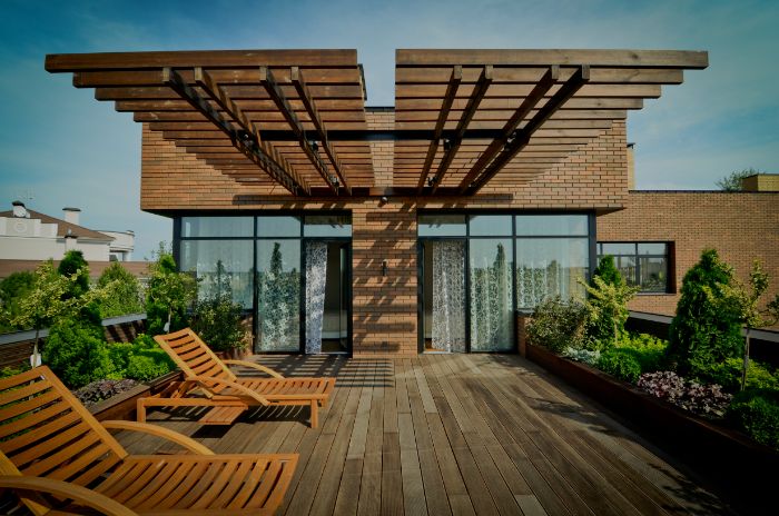 aménagement terrasse appartement boisée avec pergola en bois chaise longues et petit jardin en longueur
