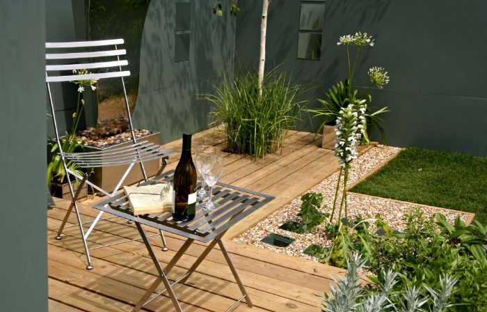 aménager sa terrasse en bois avec chaise et table metallique bordure gravier gazon vert buis autres plantes vertes