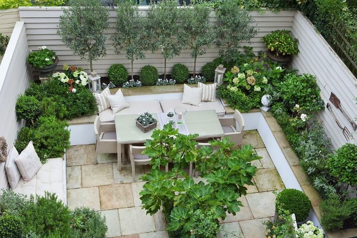 aménager une terrase extérieure en dalles de pierre salon de jardin entouré de végétation verte buis et arbres