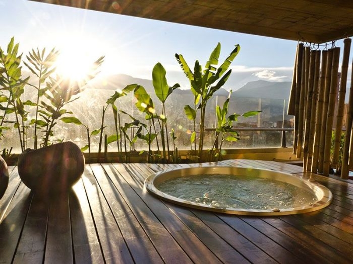 bordure de plantes vertes exotiques jaccuzzi privatif sur terrasse couverte moderne avec rideau bambou