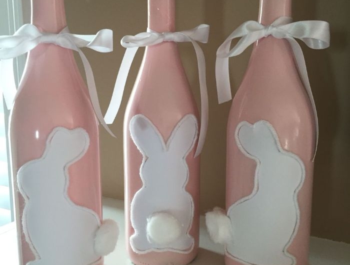 bouteilles de vin recyclées peintes de peinture rose avec motig lapin blanc à queue en coton et ruban blanc