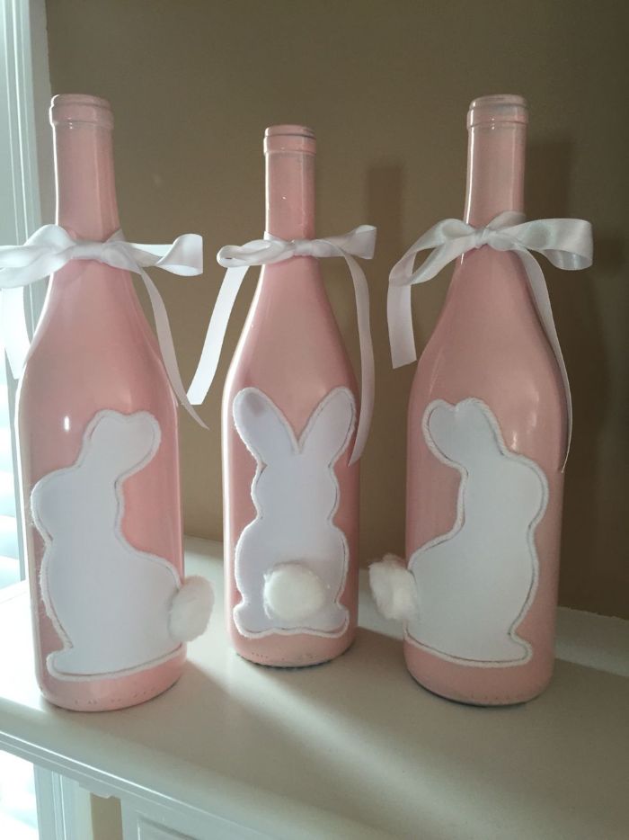 bouteilles de vin recyclées peintes de peinture rose avec motig lapin blanc à queue en coton et ruban blanc