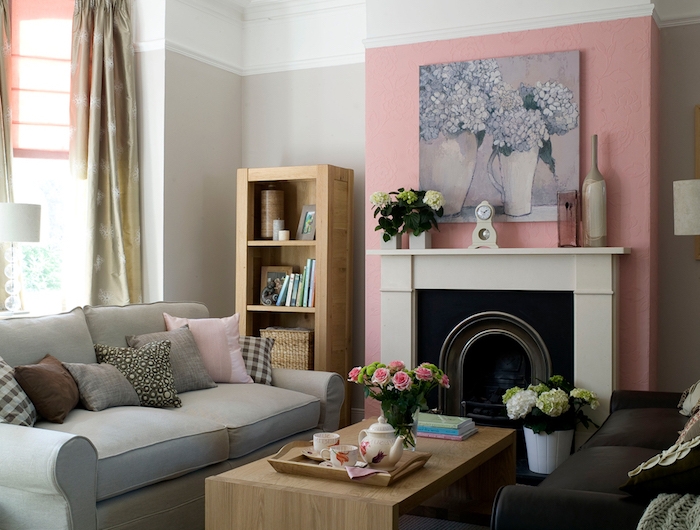 canapé gris dans un salon avec un mur en peinture vieux rose autour la cheminée