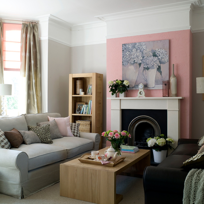 canapé gris dans un salon avec un mur en peinture vieux rose autour la cheminée