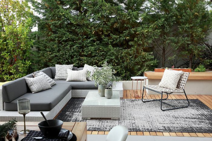 canapé et table résinte blanche assises blanches chaise tressée et métal terrasse revêtement bois arbres vegetation
