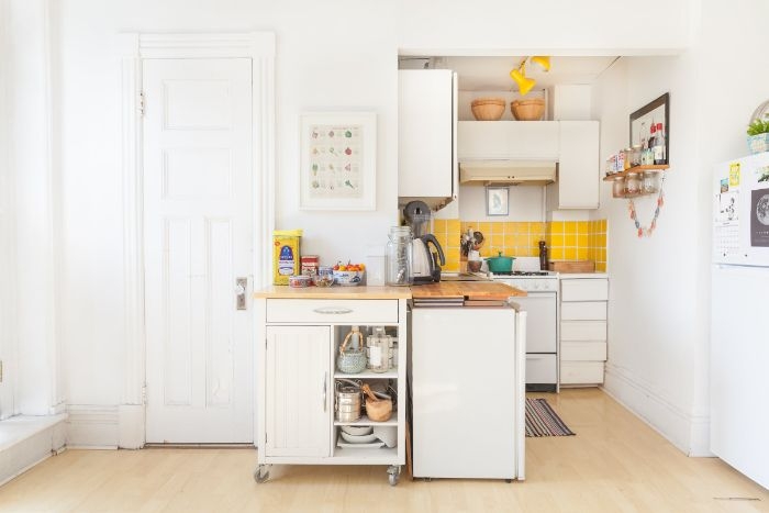 carrelage jaune dans petite cuisine ouverte en l avec pkan de travail bois sur meuble blanc ilot central amovible sur roulettes