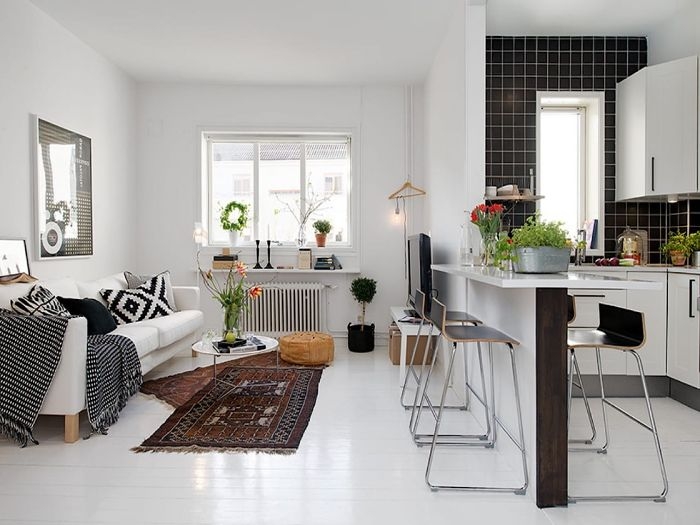 cuisine blanche carrelage noir ouverte sur un salon blanc séparation ilot de cuisine coussins plaids tapis orientaux