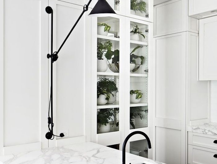 cuisine minimaliste en blanche et marbre avec une lampe de bureau et des placards en verre