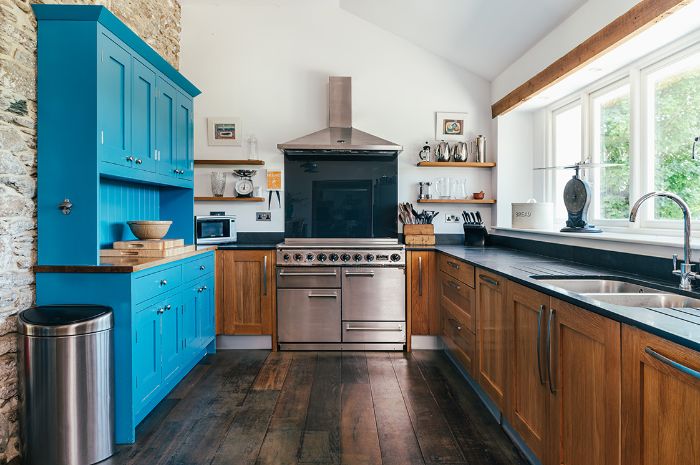 cuisine style campagne anglaise avec meuble bas bois poutre apparante parquet bois foncé armoire bleue murs blancs