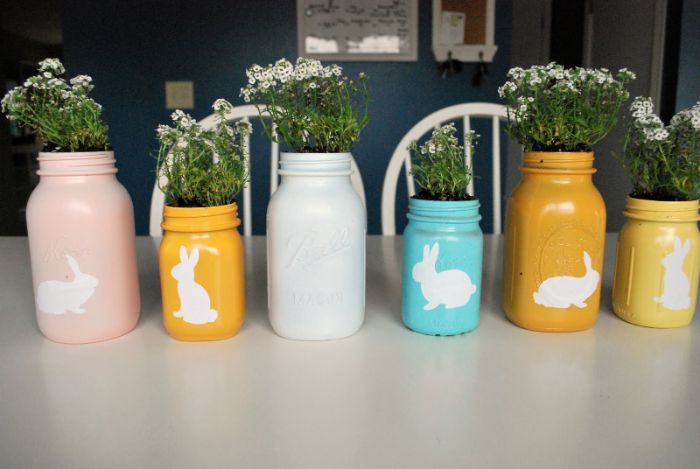 deco table paques originale avec des pots en verre recyclés peints et décorés de motid lapin avec des fleurs à l intérieur