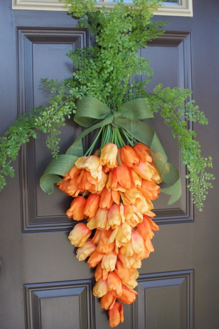 des fleurs oranges nouée d un ruban et suspendus a une porte d entrée en bois
