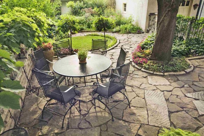 décoration de terrasse extérieure en pierre avec jardin avec arbres gazon bordure de plantes salon de jardin en table et chaises